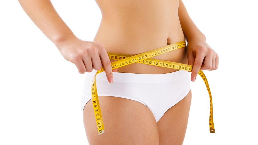 Corpo feminino com fita métrica no abdômen para ilustrar conteúdo sobre abdominoplastia.